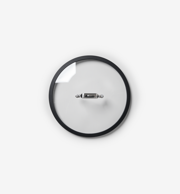 Glass pot lid with black rim and stainless steel handle, top-down view