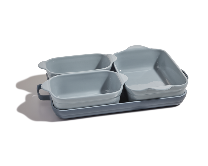 The Bakeware Set includes four light blue stoneware dishes—two small, one medium, and one large—stacked together on a white background, making a versatile addition to any ovenware collection.