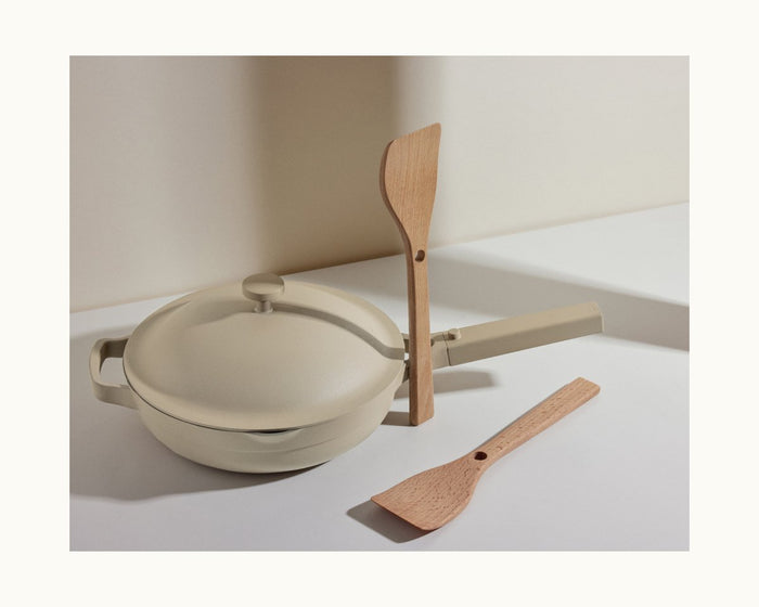 The Beechwood Spatulas set includes two natural spatulas: one nestles on the handle of a beige nonstick pan with a lid, while the other rests flat alongside versatile Always Pan accessories.