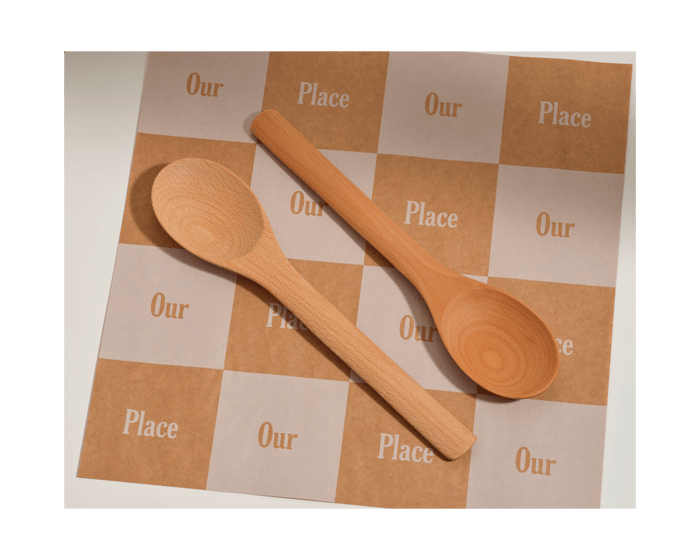 Two Beechwood Spoons rest on a checkerboard-patterned surface with alternating squares labeled Our Place in white and brown, highlighting these stylish kitchen utensils.