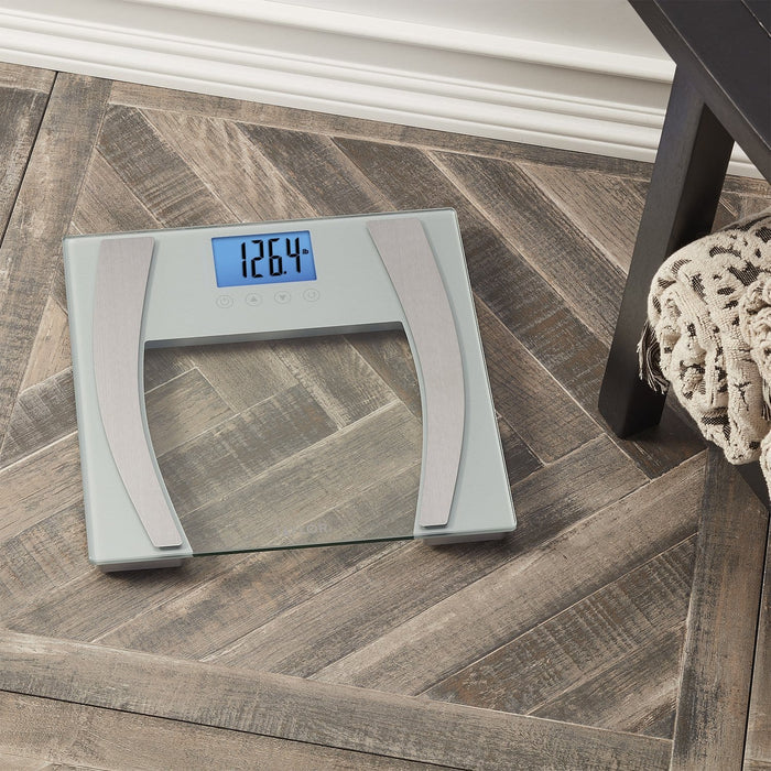 Top-down view of a glass platform bathroom scale displaying 126.4 lb on a blue backlit screen