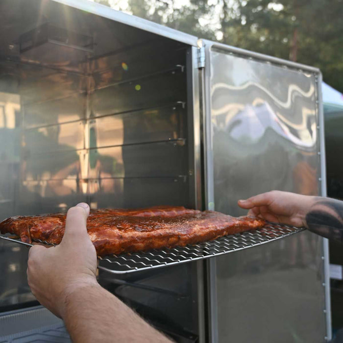 Person placing meat on stainless steel Borniak smoker grate in outdoor grill setup