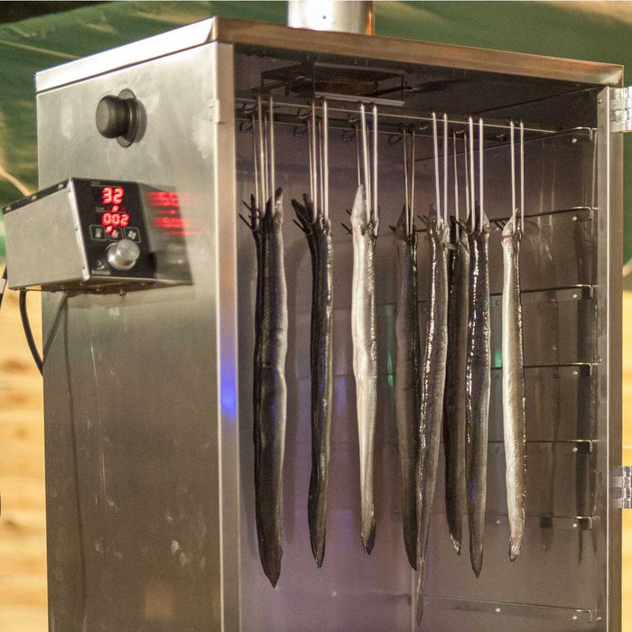 Smoked fish hanging on stainless steel hooks in smoker