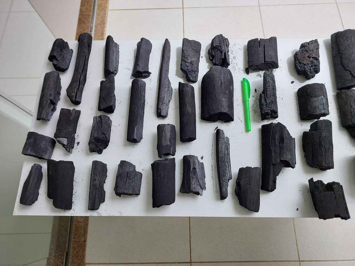 Various black charcoal pieces on white surface for grilling
