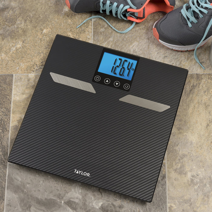 Top-down view of carbon fiber digital scale on a tiled floor with sneakers nearby and display reading 126.4 lb