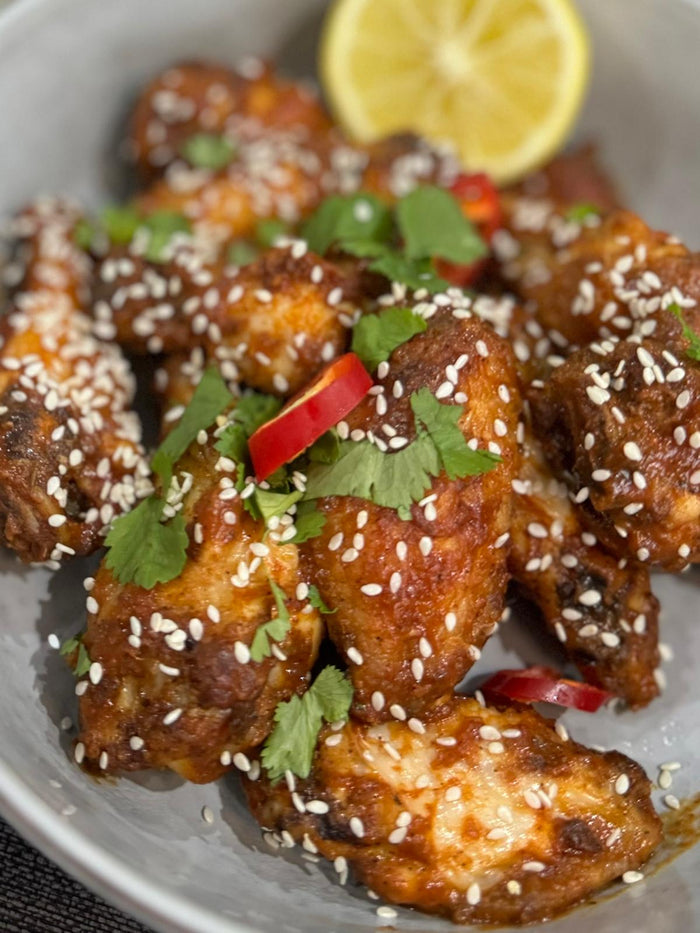 Close-up of spicy chicken wings with mango hot sauce and lemon