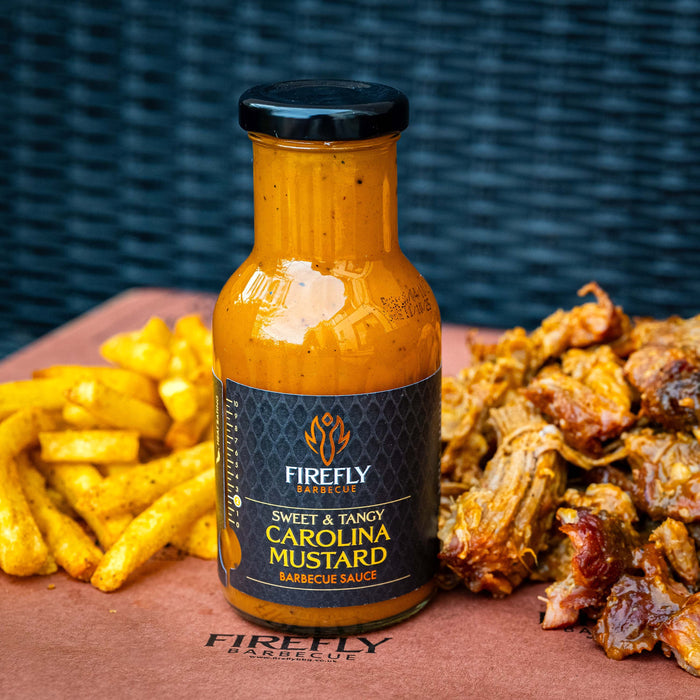 Firefly Carolina Mustard BBQ Sauce bottle placed beside pulled pork and seasoned fries, showcasing its sweet and tangy flavor pairing.