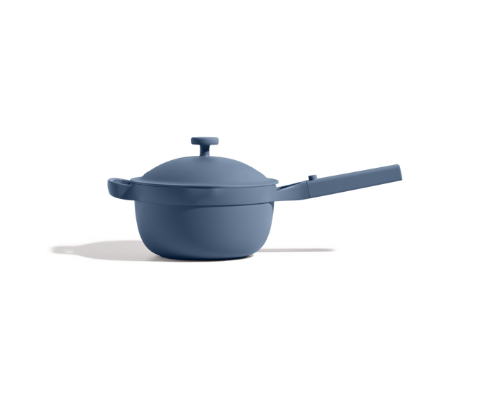The Mini Perfect Pot 2.0, a matte blue nonstick pot with a lid and long handle, is set on a plain white background with a shadow to the left.