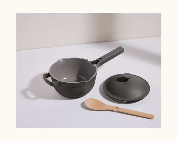 The Mini Perfect Pot 2.0, featuring a nonstick surface, handle, matching lid, and wooden spoon, is displayed on a white surface with a light background.
