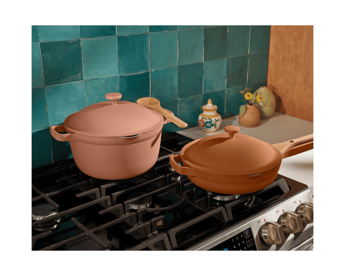 The Cookware Duo, featuring a pot and pan, sits on a gas stove in a kitchen with teal tile backsplash and decor—an ideal way to replace an 18-piece collection with these bestselling essentials.