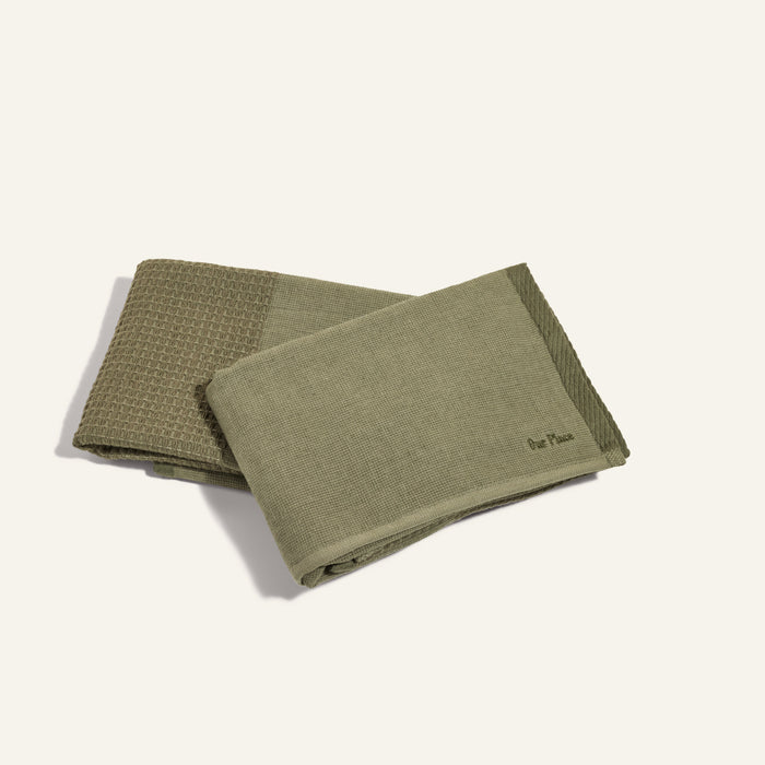 Two folded green Double Dish Towels with dual textures are stacked on a light surface.