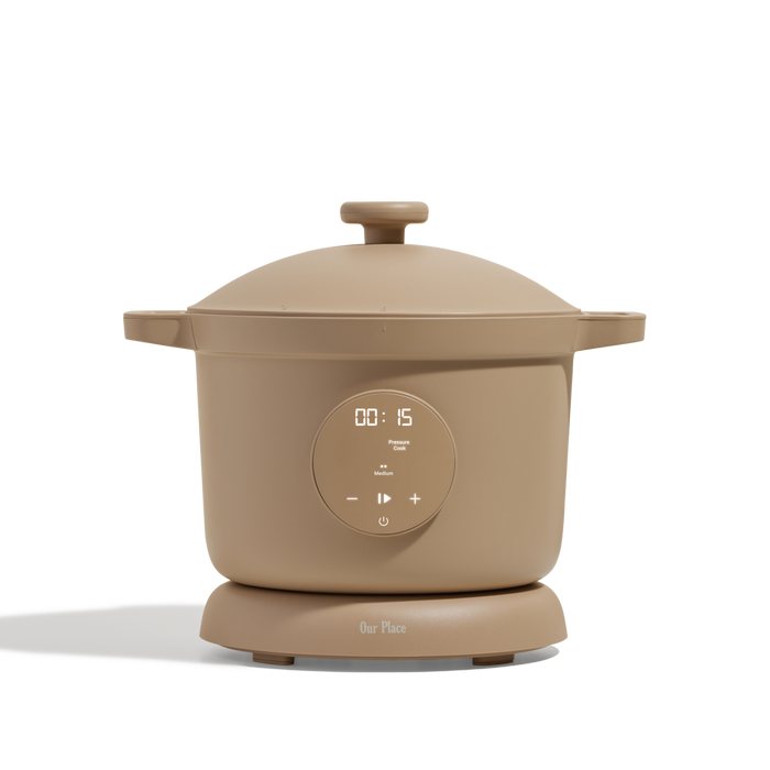 The Dream Cooker, a tan multicooker with a digital display, top lid, and side handles, is displayed against a plain white background.