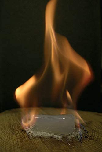 Burning solid fuel firelighter with flames on a dark background