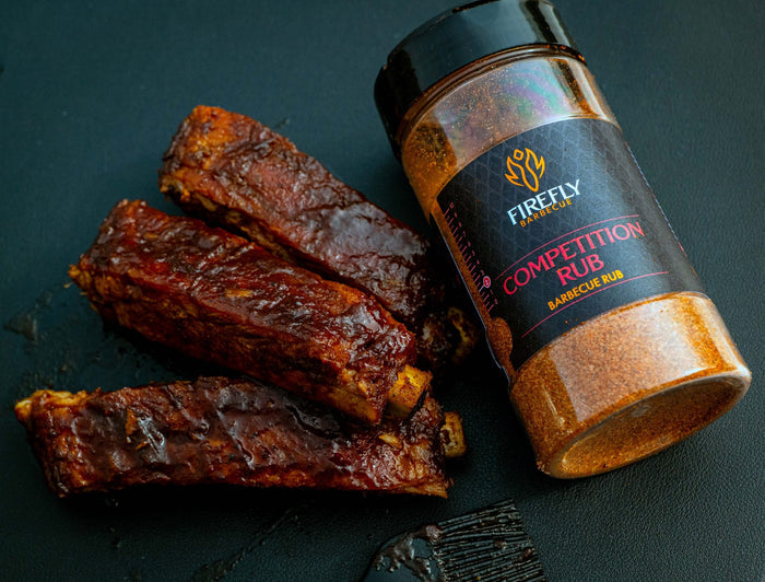 Firefly BBQ Rub jar with black lid and smoked ribs in background