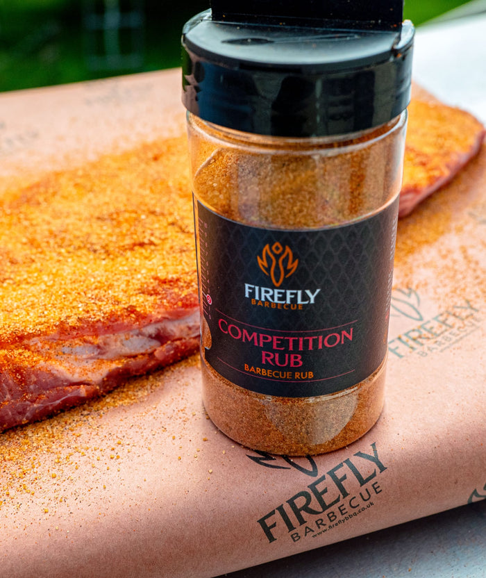 Firefly BBQ Rub jar with black lid and smoked ribs on dark surface
