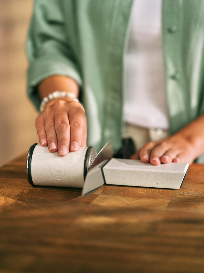 Person sharpening a knife with the Horl 3 Cruise Knife Sharpener on a wooden table