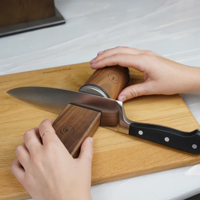 Hands using Horl Walnut Knife Sharpener with knife on wooden cutting board