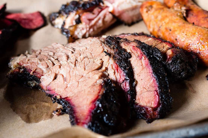 Sliced smoked brisket with charred bark and pink smoke ring, enhanced with Kansas Brisket BBQ Sauce for authentic Kansas City BBQ taste.