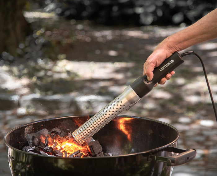 Electric charcoal starter with perforated metal tube igniting fire in a grill