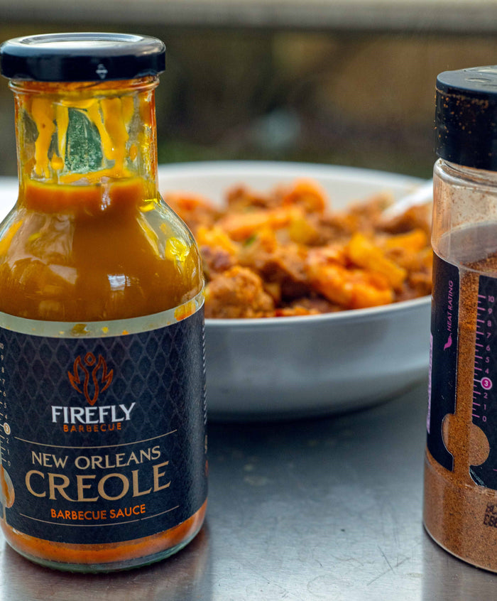 Firefly BBQ New Orleans Creole Sauce bottle next to a bowl of shrimp gumbo, showcasing its use in authentic Creole cuisine.
