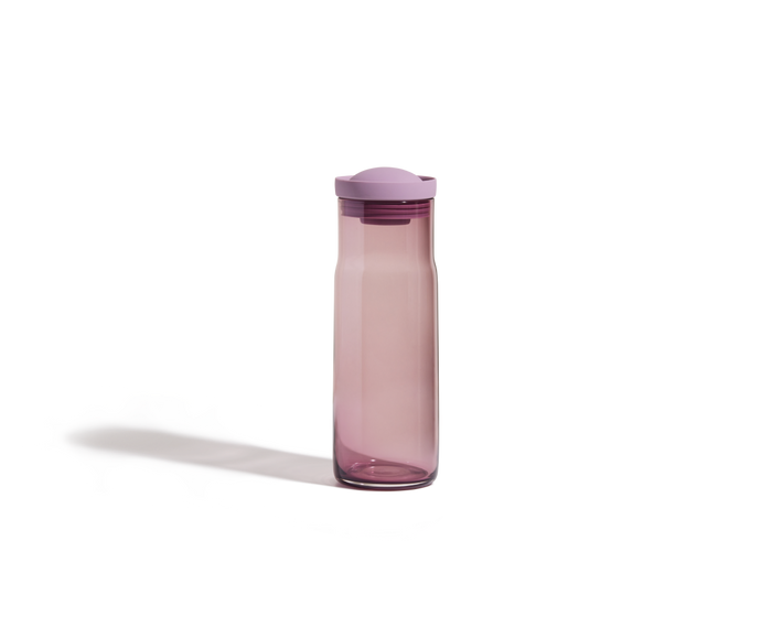 The Night + Day Carafe is a tall, translucent purple water bottle with a matching purple cap, standing upright on a plain white background.