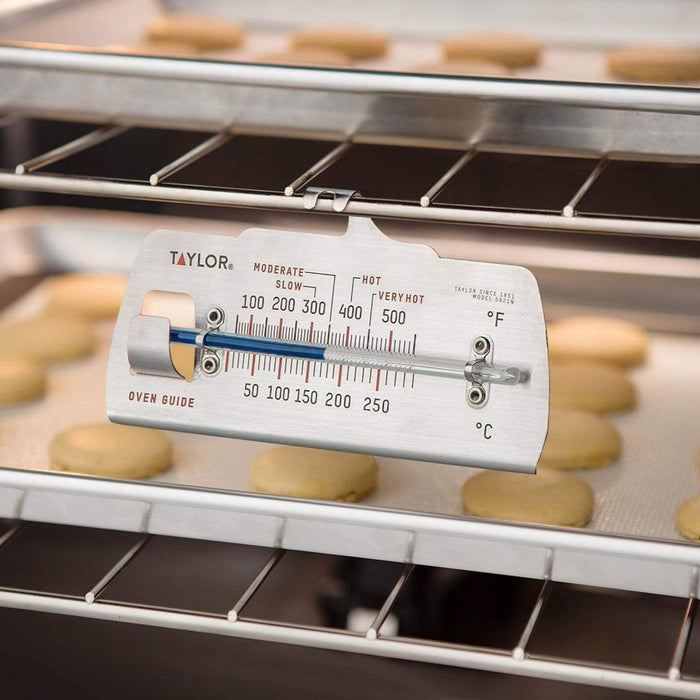 Taylor oven guide thermometer clipped to a rack above cookies baking on trays