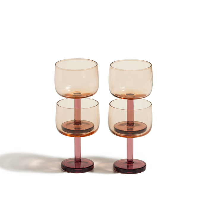 The Party Coupes are a set of four amber-tinted glass goblets with pink stems and bases, arranged in two rows on a white background—perfect colourful drinkware for serving your favorite party beverage.