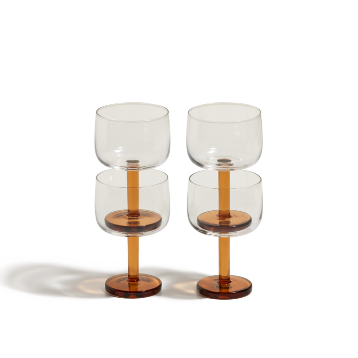 Four Party Coupes with amber stems and bases are arranged in two stacked pairs against a white background, bringing a vibrant touch to your drinkware—perfect for serving beverages at any party.