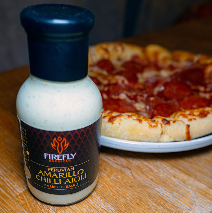 Peruvian Amarillo Chilli Aioli bottle next to pizza