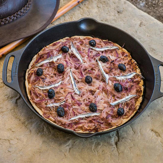 Cast iron skillet with cooked pizza and toppings