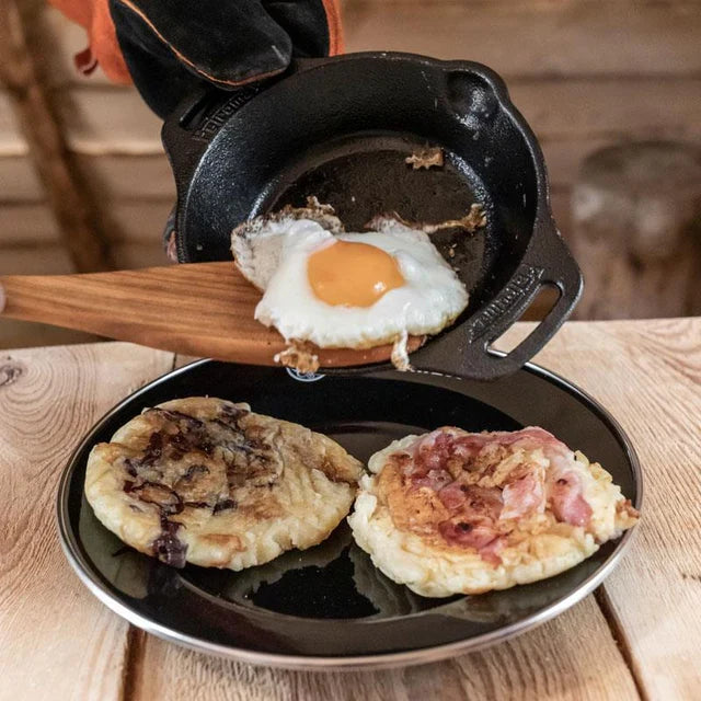 Cast iron skillet with fried eggs on wooden table