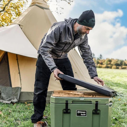 Man applying Petromax adhesive pad to green cool box outdoors