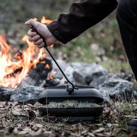 Person using Petromax Lid Lifter to handle Dutch oven lid outdoors