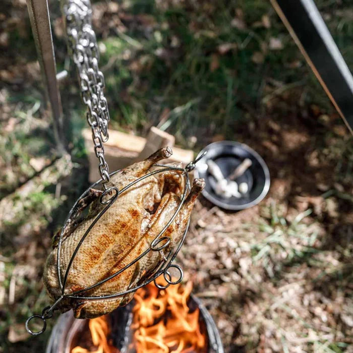 Fish being cooked over an open flame using a metal skewer