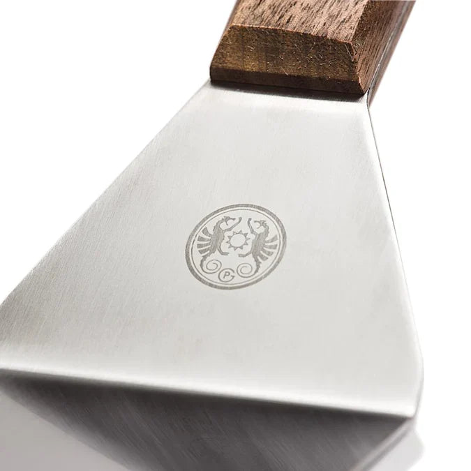 Close-up of stainless steel spatula with engraved logo and wooden handle