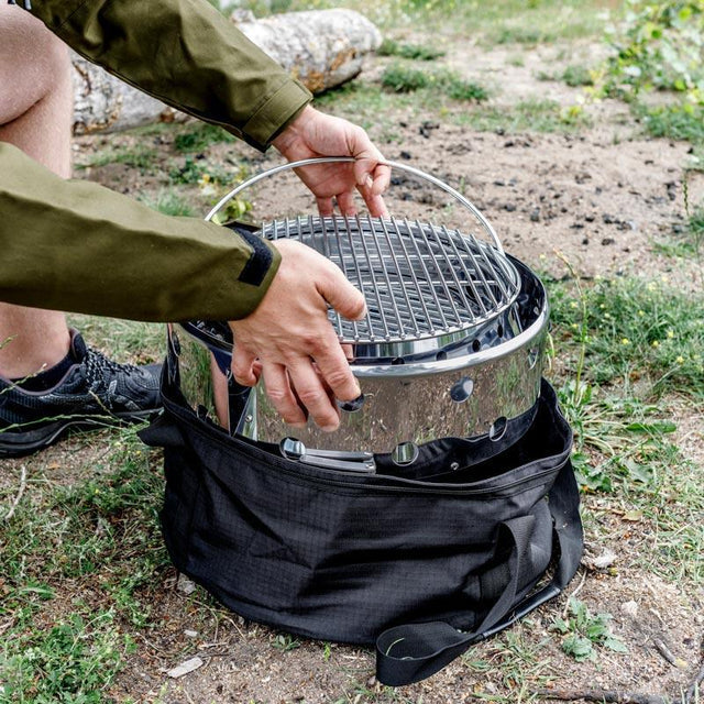 Outdoor grill in a black transport bag with handle for camping or outdoor cooking