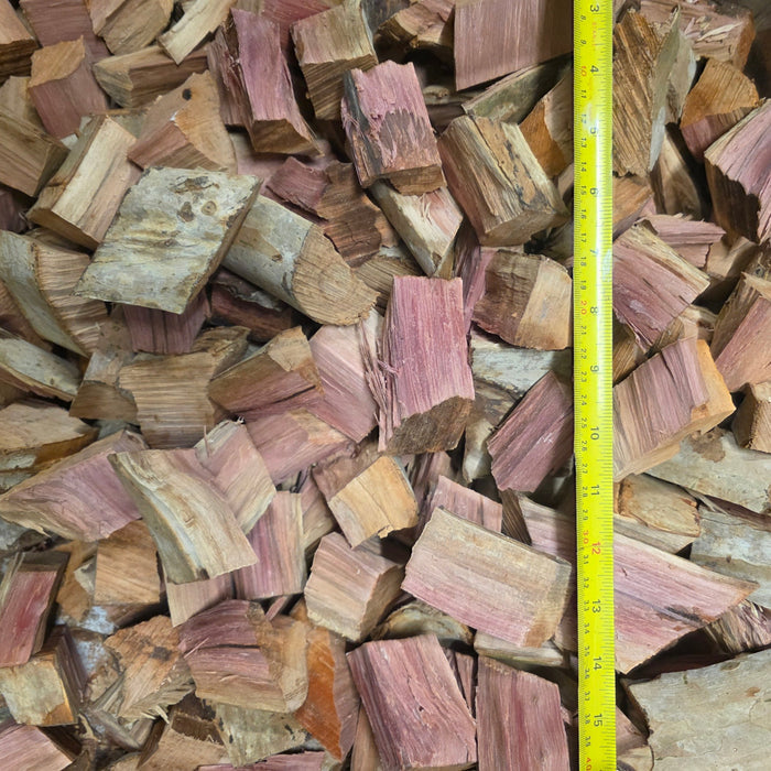 Person holding wood chunks with pinkish hue for smoking and barbecue