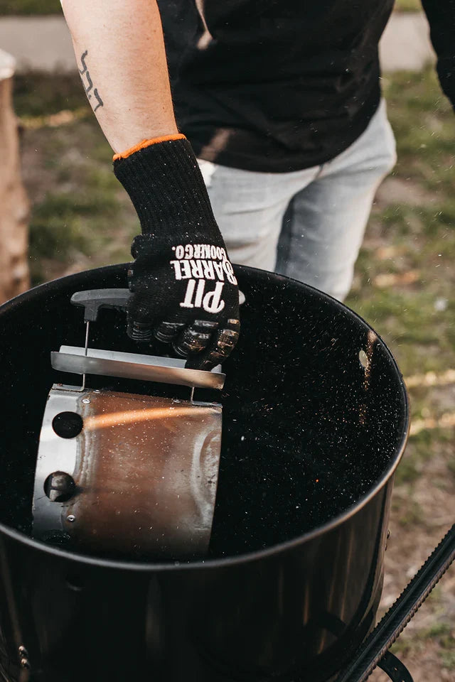 User placing Pit Barrel Chimney Starter into grill, showcasing ease of use and compatibility with Pit Barrel Cooker systems.