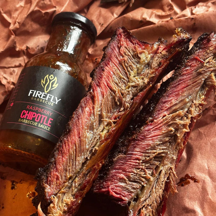 Raspberry Chipotle BBQ Sauce bottle with grilled ribs