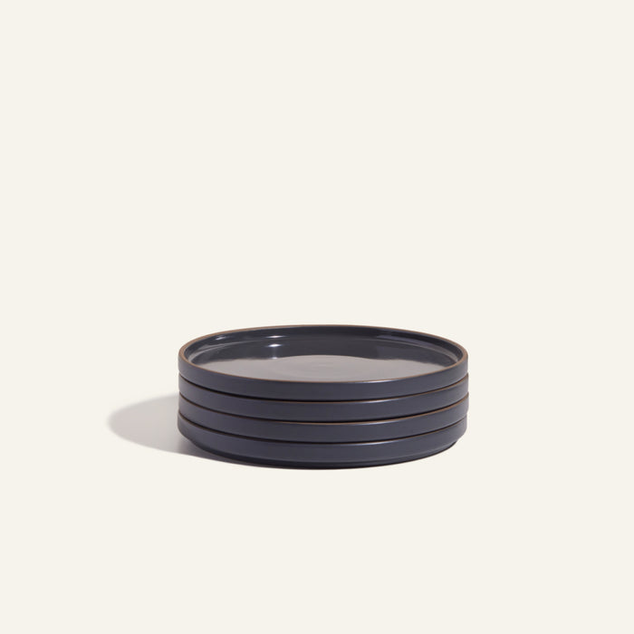 A stack of four round, dark blue hand-glazed Salad Plates rests against a plain light background, highlighting elegant tableware.