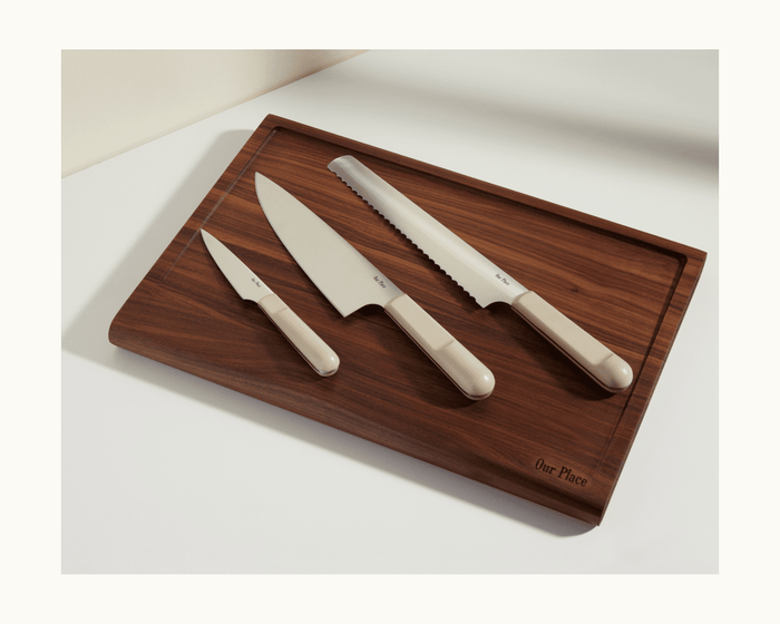 A wooden cutting board with three knives—a paring knife, a chef’s knife, and the Serrated Slicing Knife, each with beige handles and ultra sharp blades—arranged neatly on top.