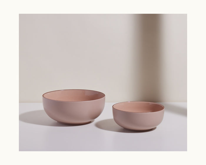 Two matte pink Serving Bowls—one large, one small—are arranged side by side on a white surface with a neutral backdrop, creating an elegant tableware set for stylish serving.
