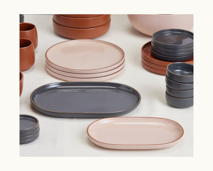 Serving Platters in muted pink and gray tones are neatly arranged on a white surface.