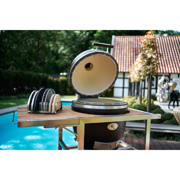 Outdoor BBQ setup with stainless steel accessory rack holding grill tools, on wooden table