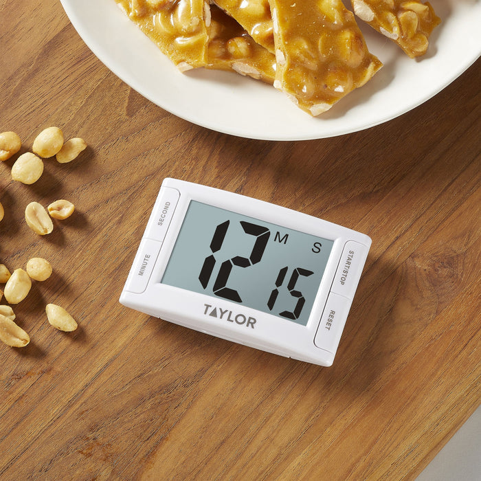 Close up of a white Super Readout Timer on a wooden table beside a plate of pretzels