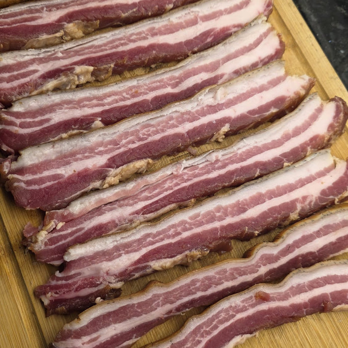 Raw bacon strips on wooden cutting board