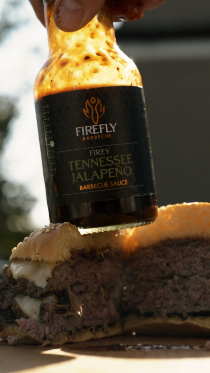 Pouring Firefly Tennessee Jalapeño BBQ Sauce on a burger
