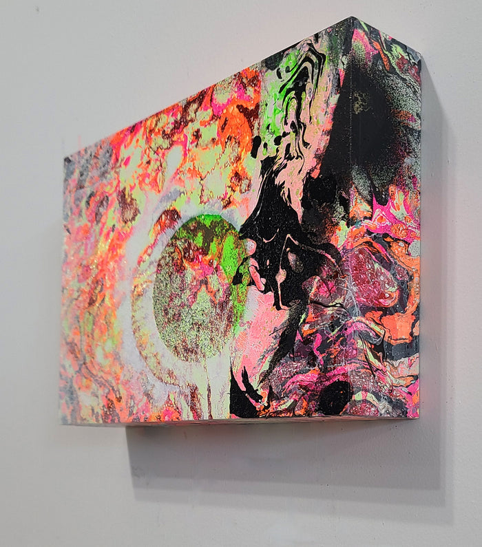 The artwork 'The Shadow and the Moon' features a vibrant abstract composition with swirling neon pink, fluorescent green, and coral hues against a dramatic black background. The piece showcases dynamic fluid textures created through mixed media techniques on wood, with a distinctive circular moon-like form emerging from the chaotic interplay of colors by Millie Benson.
