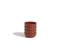 A stack of four Tiny Bowls, crafted from brown ceramic and designed for modern tableware settings, is arranged on a plain white background with a shadow cast to the left.