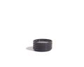 The Tiny Plates are small, round, dark-colored ceramic dishes with three horizontal ridges, ideal for serving snacks or adding to your tableware set. Set against a plain white background.